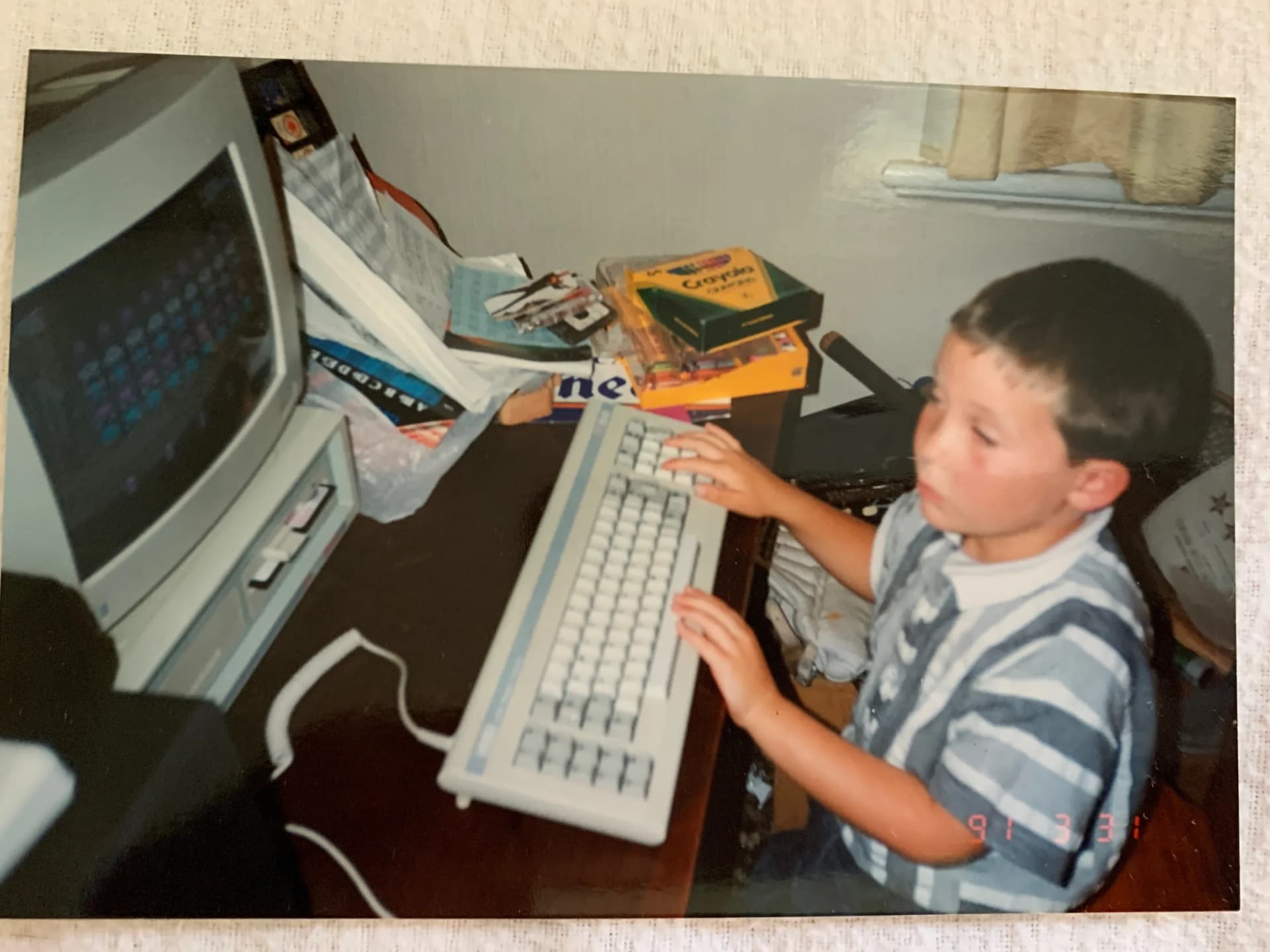 Five-year-old Nic Fouhy at a beige CRT computer in 1991, with Crayola crayons and an alphabet book on the desk